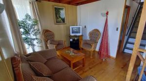 uma sala de estar com um sofá e cadeiras e uma televisão em Casa El Tabo em El Tabo