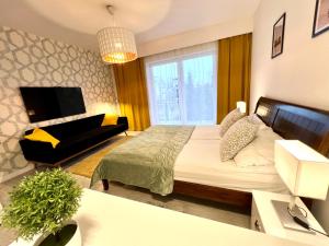 a bedroom with a bed and a couch and a television at WiLLA APART in Władysławowo