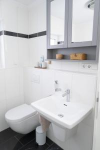 a white bathroom with a sink and a toilet at Ferienwohnung Rheinauen in Germersheim