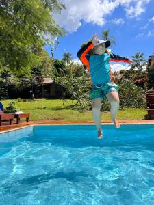 a young girl jumping into a swimming pool at Mainumby- Colibri Posada in Puerto Iguazú