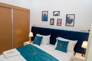 um quarto com uma cama com lençóis e almofadas azuis em Hotel Golden Sunset Dakhla em Dakhla
