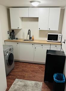 a kitchen with white cabinets and a sink and a microwave at Comfy Home in Trail