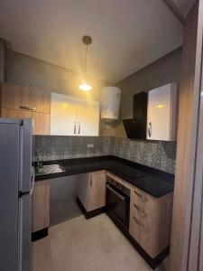 uma cozinha com armários brancos e um balcão preto em Appart prestige de luxe em Marrakech