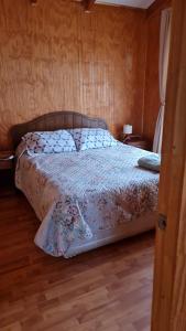 a bed in a bedroom with a wooden floor at Cabañas Canto del Tiuque in Pishuinco