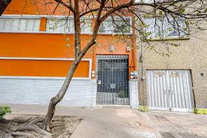 un edificio arancione con una porta e un albero di Cadetes 47 #102 a Città del Messico