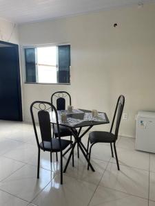 a dining room table with four chairs and a table and a window at Apto Serras Gerais in Dianópolis