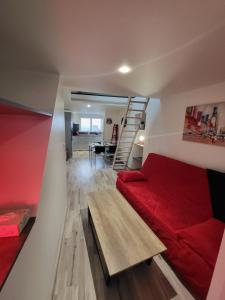 - une petite chambre avec un lit rouge et un escalier dans l'établissement Margotte, aux Pieux