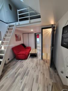 - un salon avec un canapé rouge et des escaliers dans l'établissement Margotte, aux Pieux