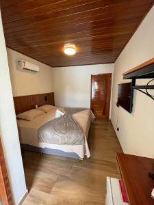 1 dormitorio con 1 cama y TV en Guarapari Park en Guarapari