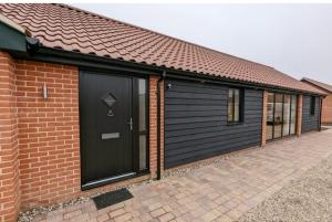 a garage with a black door and a brick building at Meadow View Lodges in Bury Saint Edmunds