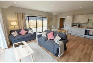 a living room with two blue couches and a kitchen at Meadow View Lodges in Bury Saint Edmunds