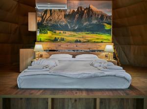 a bedroom with a large bed with a painting on the wall at Daxvalley Glamping in Tsalka