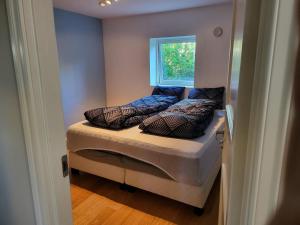 um pequeno quarto com uma cama com almofadas em Nesttunveien appartments em Bergen