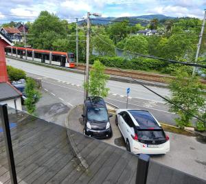Nesttunveien appartments في بيرغِن: سيارتين متوقفتين في موقف للسيارات بجوار قطار