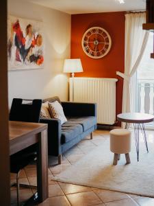 a living room with a couch and a clock on the wall at B&B Roudenhaff in Echternach