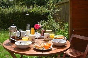 una mesa de madera con desayuno en The Owl Box: self-contained private annex & garden en Horseheath