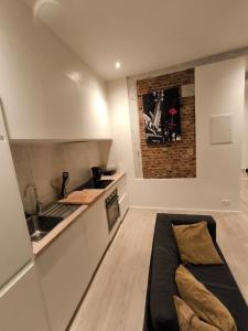eine Küche mit weißen Schränken und einem Sofa in einem Zimmer in der Unterkunft Appartement LA BOURSE in Brüssel