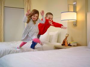 a boy and a girl jumping on a bed at Sonesta ES Suites Boston Burlington in Burlington