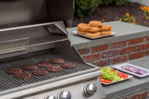 a grill with hamburgers and burgers and a plate of food at Staybridge Suites Burlington - Boston, an IHG Hotel in Burlington