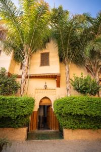 a house with two palm trees in front of it at Riad Mazar in Fez