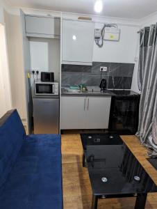 a small kitchen with a blue couch and a table at Luxury flat in Nevendon