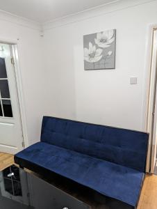 a blue couch in a room with a wall at Luxury flat in Nevendon