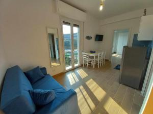 un soggiorno con divano blu e una cucina di FARO vicino al mare BluDiPietraLigure a Pietra Ligure