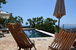 two chairs and an umbrella next to a swimming pool at Peaceful & Secluded Retreat House Kod Kapetana Hvar in Veliko Grablje