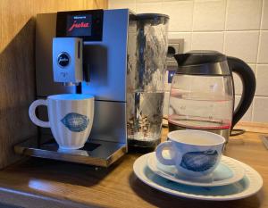 une cafetière et deux tasses sur un comptoir dans l'établissement Urlaub beim Käptn! Freistehendes Premium Nordsee-Ferienhaus mit Fahrrädern, Stellplatz und Garten, 150m zur Nordsee, à Butjadingen 29 autres photos