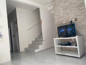 a living room with a tv and a staircase at Chalé em Praia Bela Paraíba in Pitimbu