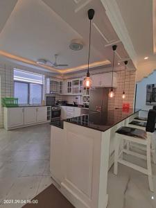 a large kitchen with white cabinets and black counter tops at Ayaa Luxury Apartment 3rd Floor Zanzibar in Ngambo