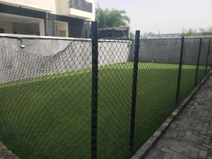 une clôture à maillons de chaîne devant un champ d'herbe dans l'établissement Shaunz apartments, à Lagos