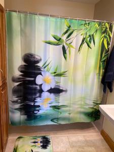 La salle de bains est pourvue d'un rideau de douche avec un zen buddha et des fleurs. dans l'établissement Healing / Spiritual Oasis, à Otsego