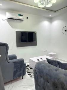 a living room with two chairs and a tv on a wall at Blueocean.cog in Benin City