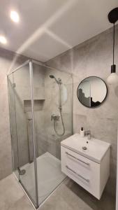 a bathroom with a shower and a sink and a mirror at Słoneczny apartament w centrum Gdyni in Gdynia