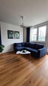 a living room with a blue couch and a table at Słoneczny apartament w centrum Gdyni in Gdynia