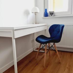 a blue chair sitting next to a white desk at Słoneczny apartament w centrum Gdyni in Gdynia