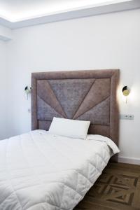 a bedroom with a white bed with a large headboard at APARTAMENTO EN CALLE RECOGIDAS in Granada