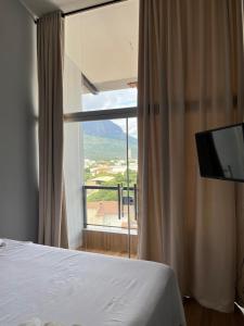 um quarto com uma cama e uma grande janela em Skyloft Chalé em Governador Valadares