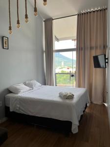 um quarto com uma cama com lençóis brancos e uma janela em Skyloft Chalé em Governador Valadares