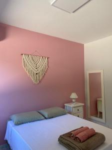 1 dormitorio con cama y pared de color rosa en Recanto aconchegante no Campeche Apart 03 - 50m da praia -, en Florianópolis