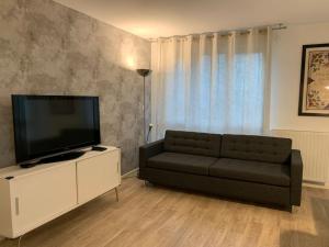 a living room with a couch and a flat screen tv at La demeure des Rois - Parking - Metro - Stade de France in Saint-Denis