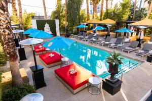 einen Blick über einen Pool mit Stühlen und Sonnenschirmen in der Unterkunft The Lexi Las Vegas in Las Vegas