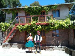 un hombre y una mujer parados frente a un edificio con vides en INKA LAKE Taquile Lodge, en Huillanopampa