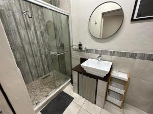 a bathroom with a shower and a sink and a mirror at Tula Baba Game Lodge in Brits