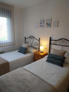 a bedroom with two beds and a table with a lamp at Piso Beiramar in Pontevedra