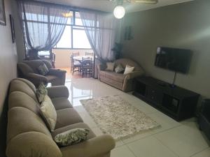 ein Wohnzimmer mit einem Sofa und einem TV in der Unterkunft Serenity Seascapes in Amanzimtoti