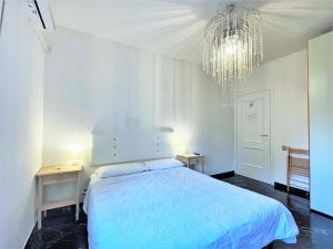 a white bedroom with a bed and a chandelier at Airport Suite in Pisa