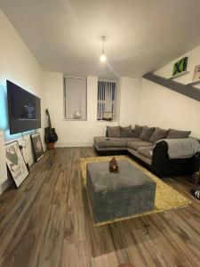 ein Wohnzimmer mit Sofa und Fernseher in der Unterkunft New London Apartment- 20mins from Central City in Romford