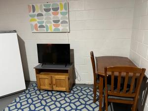 una mesa pequeña con TV en un soporte de madera y una mesa pequeña con en Southside Lodge, en Franklin Village
